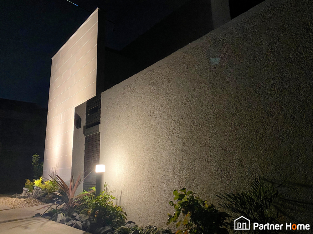 愛知県名古屋市緑区にて外構工事エクステリアが完成しました。シンプルモダンのオープン外構です。ハウスメーカーで建てられた外壁が素敵な住宅に合わせ駐車スペースを直線が綺麗な土間コンクリートと綺麗な白い砂利仕上げといたしました。アプローチから玄関、お庭に繋がるスペースには大きなブロック積み門塀を作成し、ポスト・インターホン・表札を埋め込み、住宅に合ったデザインを致しました。照明が設置されている住宅まわりにはグレー色の割栗石と植栽を設置。